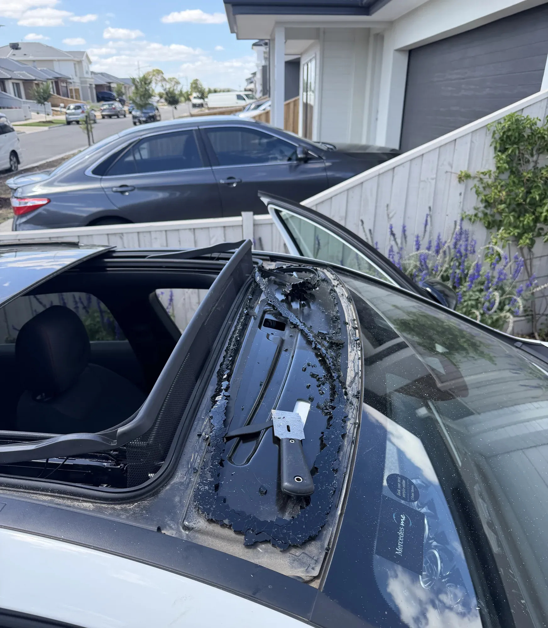 Rear quarter glass removed from a sedan showing the cleaned bonding frame during a mobile side window replacement